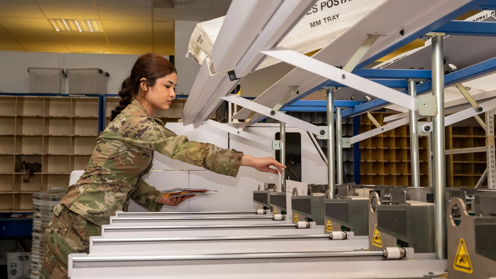 A postal worker sorting incoming letters and parcels at a military post office in Germany