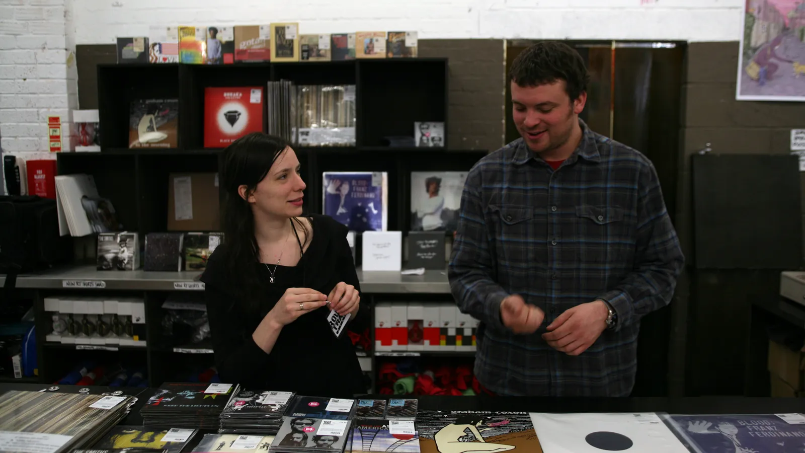 A customer and shop assistant at the counter of Rough Trade East record shop in London on Record Store Day, with stacks of vinyl on the counter